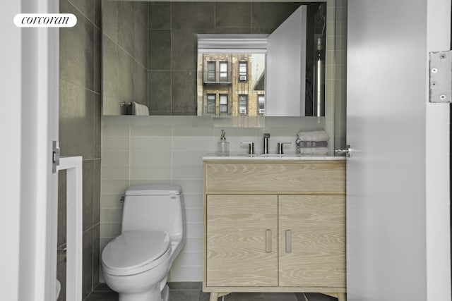 bathroom with toilet, vanity, and tile walls