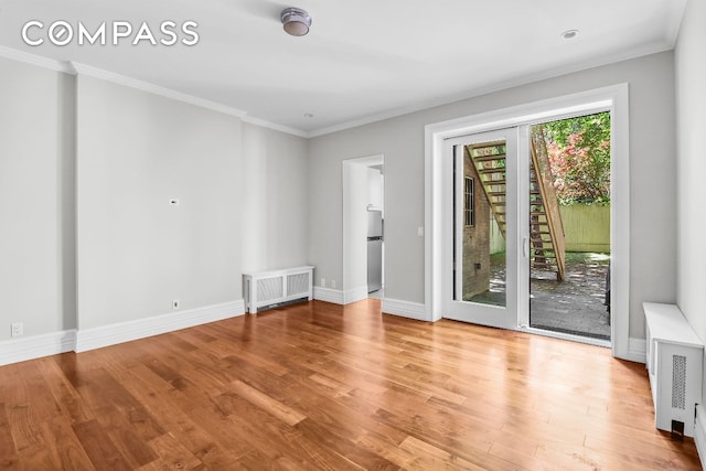 empty room with ornamental molding, radiator, and light hardwood / wood-style floors