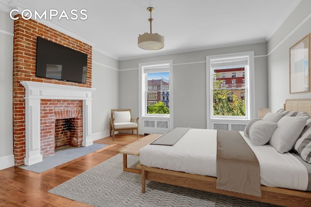 bedroom featuring hardwood / wood-style flooring, ornamental molding, and a fireplace