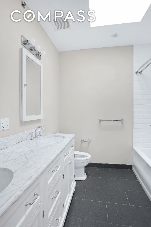 full bathroom with vanity, tiled shower / bath, tile patterned floors, and toilet