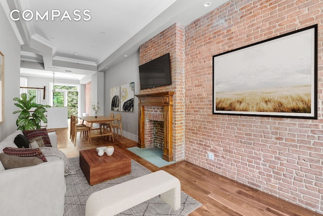 living room with crown molding, brick wall, and light hardwood / wood-style flooring