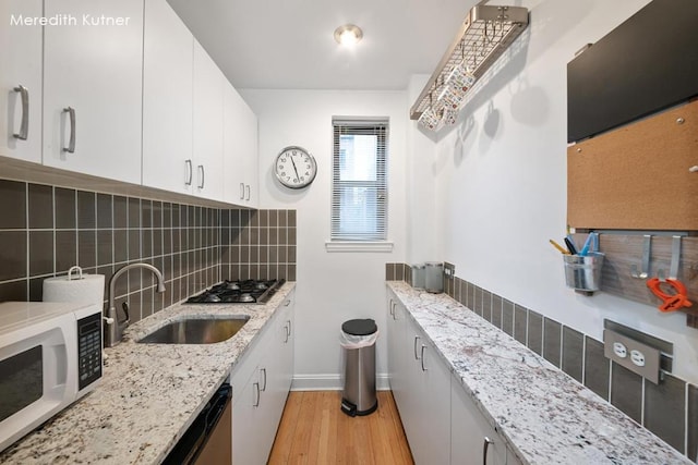 kitchen featuring white cabinetry, tasteful backsplash, light stone counters, and sink