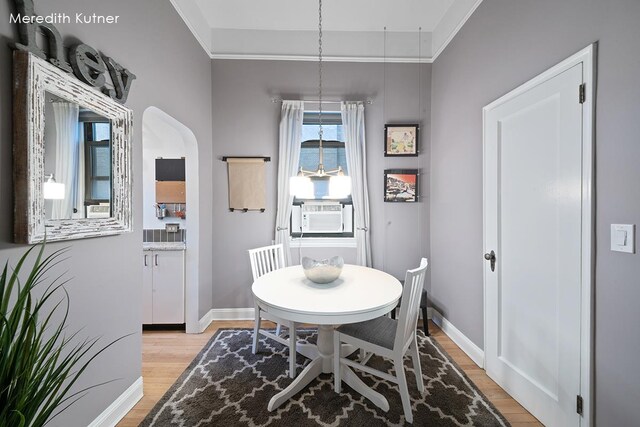 dining area featuring crown molding, cooling unit, and light hardwood / wood-style floors