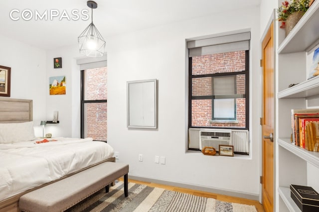 bedroom featuring cooling unit, baseboards, and light wood-style floors