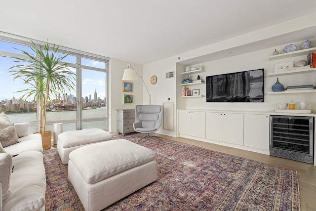 living room with floor to ceiling windows, hardwood / wood-style floors, bar, a water view, and beverage cooler