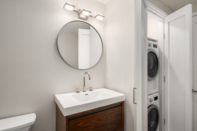 bathroom with vanity, stacked washer / drying machine, and toilet