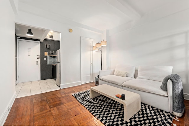 living area featuring beamed ceiling and baseboards