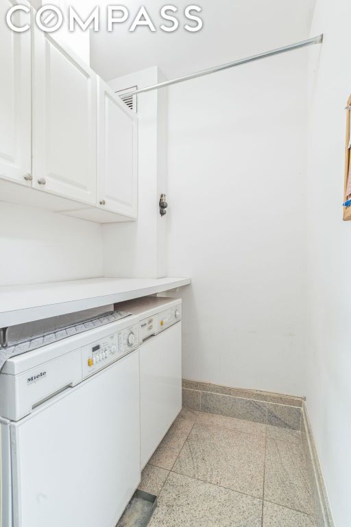 clothes washing area featuring cabinets and washer and clothes dryer