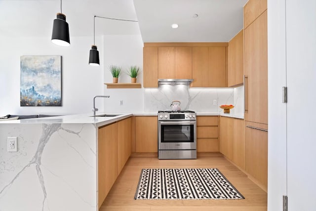 kitchen with gas range, kitchen peninsula, sink, hanging light fixtures, and light stone counters