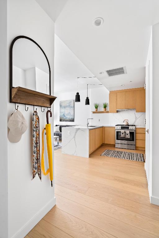 kitchen featuring visible vents, light countertops, open shelves, gas stove, and decorative light fixtures