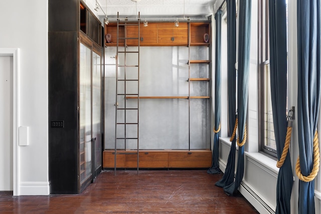 interior space with dark wood-style flooring, a baseboard radiator, and track lighting