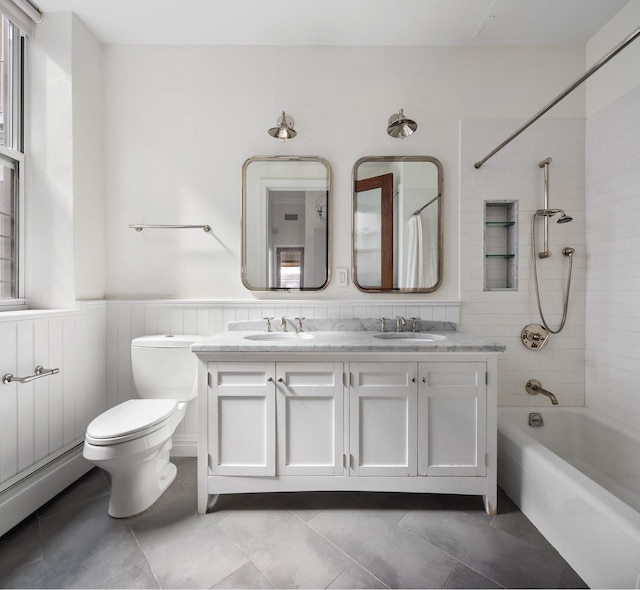 full bathroom with shower / washtub combination, a wainscoted wall, a sink, and toilet