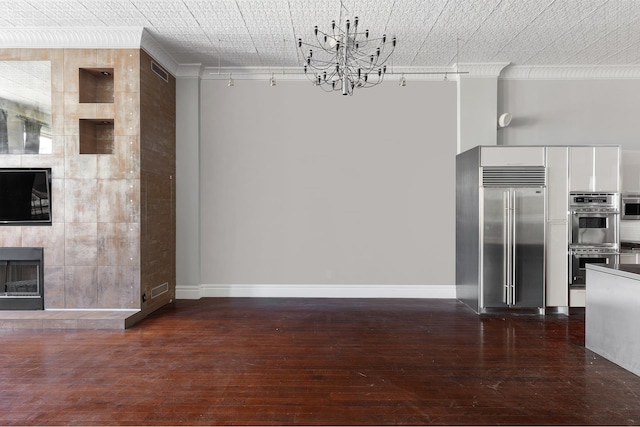 unfurnished living room with a chandelier, ornamental molding, a tile fireplace, and dark wood finished floors