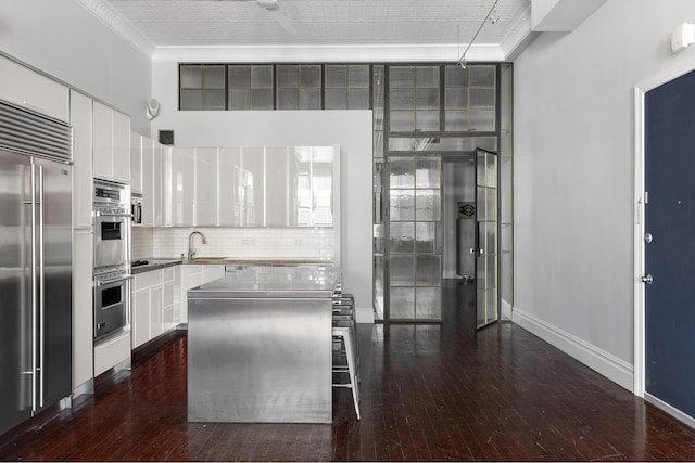 kitchen featuring white cabinets, decorative backsplash, a kitchen island, a kitchen breakfast bar, and stainless steel appliances