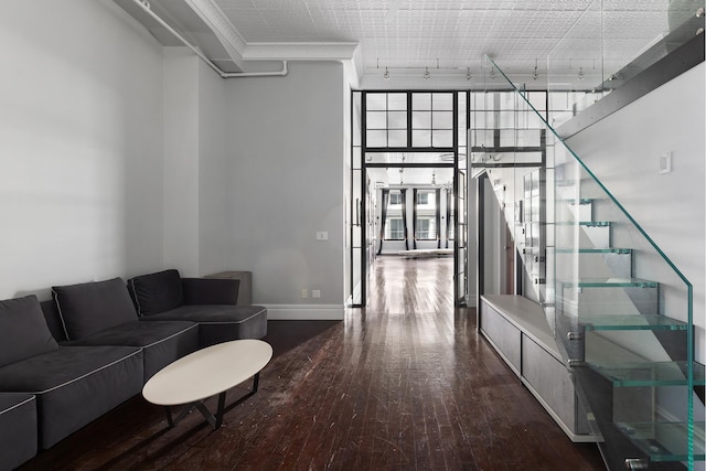 living room featuring wood finished floors, baseboards, stairs, expansive windows, and rail lighting