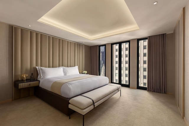 bedroom featuring a wall of windows, light colored carpet, and a raised ceiling