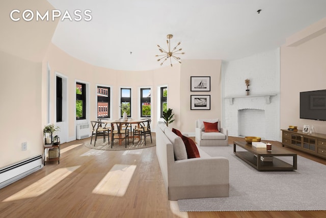 living area featuring radiator, baseboard heating, light wood-style floors, a fireplace, and a chandelier