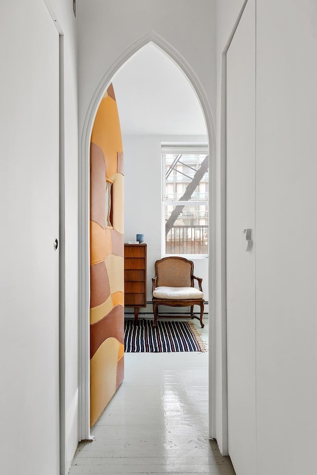 hallway with a baseboard heating unit and arched walkways