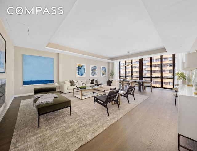 living room featuring wood-type flooring, a raised ceiling, and floor to ceiling windows