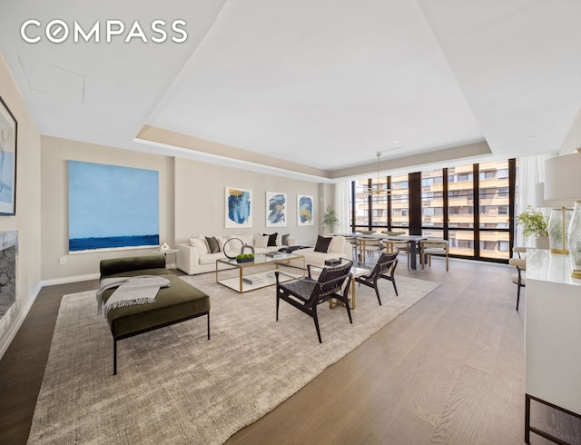 living room with baseboards, a raised ceiling, and wood finished floors