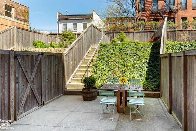 view of patio / terrace with a fenced backyard, stairs, and outdoor dining area