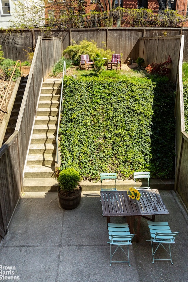 view of yard featuring a patio, outdoor dining space, a fenced backyard, and a garden