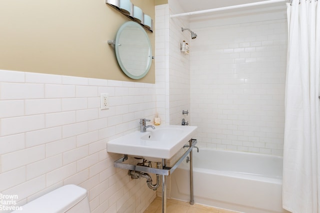 full bathroom with wainscoting, toilet, tile patterned floors, shower / bathtub combination with curtain, and tile walls