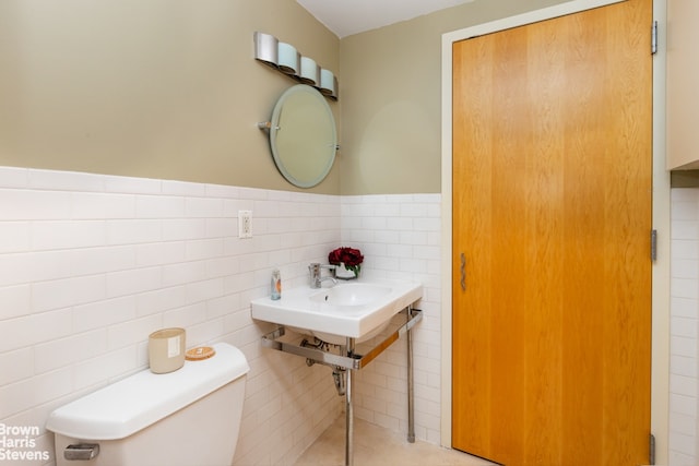 bathroom with a wainscoted wall, tile walls, and toilet