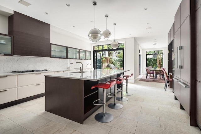 kitchen featuring white cabinets, light countertops, an island with sink, modern cabinets, and glass insert cabinets