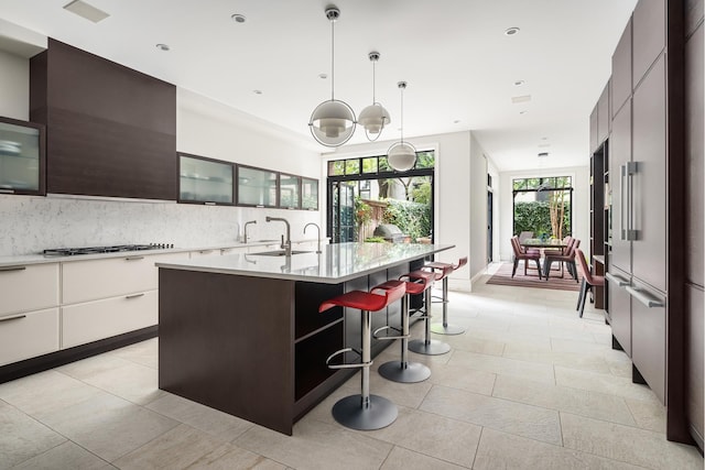 kitchen with a kitchen bar, modern cabinets, light countertops, and a sink