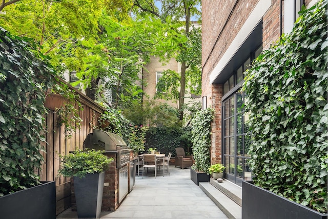 view of patio with outdoor dining space, exterior kitchen, and grilling area