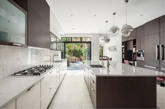 44 W 90th St, New York City, NY 10024 - kitchen featuring stainless steel gas stovetop, modern cabinets, tasteful backsplash, light stone counters, and dark brown cabinetry