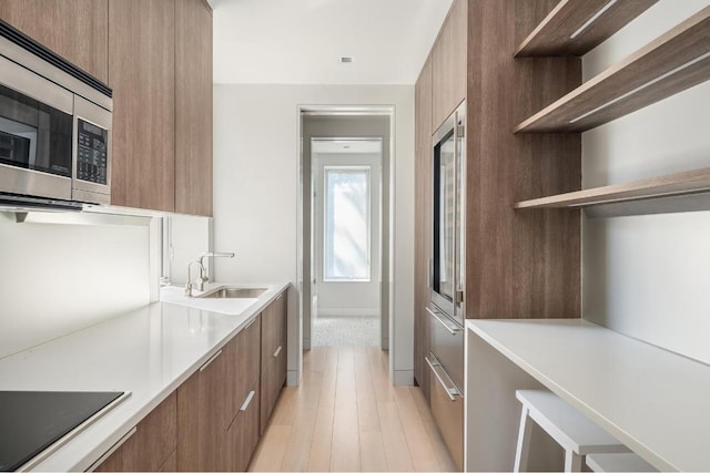 kitchen featuring modern cabinets, stainless steel microwave, black electric stovetop, light countertops, and open shelves