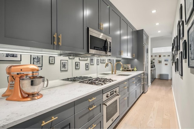 kitchen featuring stainless steel appliances, light wood finished floors, recessed lighting, and light stone countertops