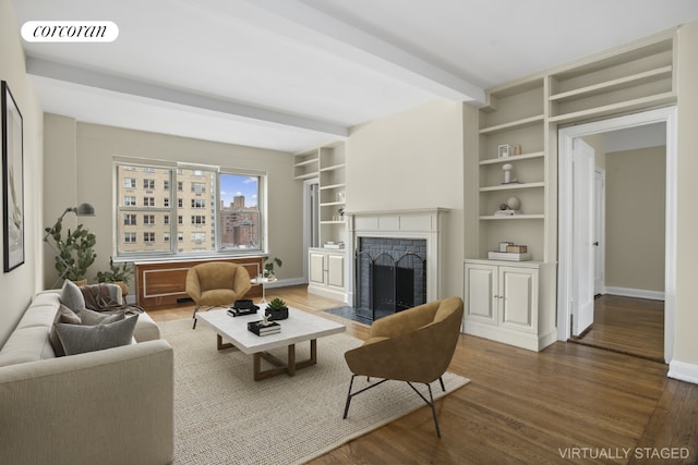 living room with a brick fireplace, dark wood-type flooring, built in features, and beamed ceiling