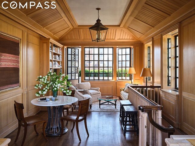 living area featuring wood walls, crown molding, beam ceiling, and coffered ceiling