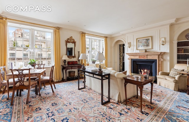 living area with light wood-style floors, a lit fireplace, and crown molding
