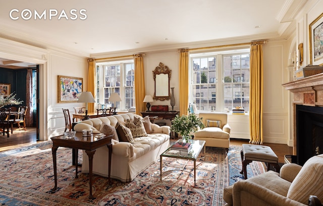 living room with a decorative wall, a fireplace, crown molding, and wood finished floors