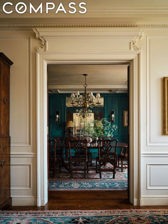 interior space featuring a chandelier, dark wood-type flooring, wooden walls, and ornamental molding