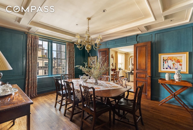 dining area featuring coffered ceiling, a decorative wall, wood finished floors, and a chandelier