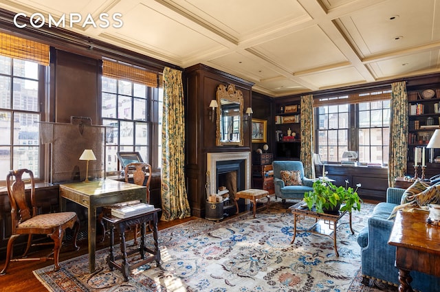 living area featuring a wealth of natural light, a fireplace, coffered ceiling, and wood finished floors