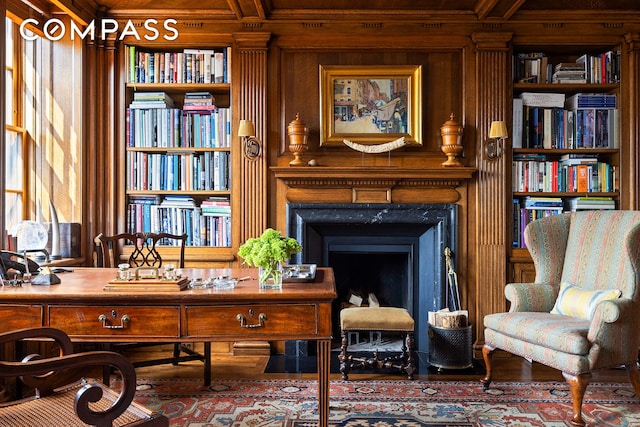 sitting room with crown molding, wood walls, and built in shelves
