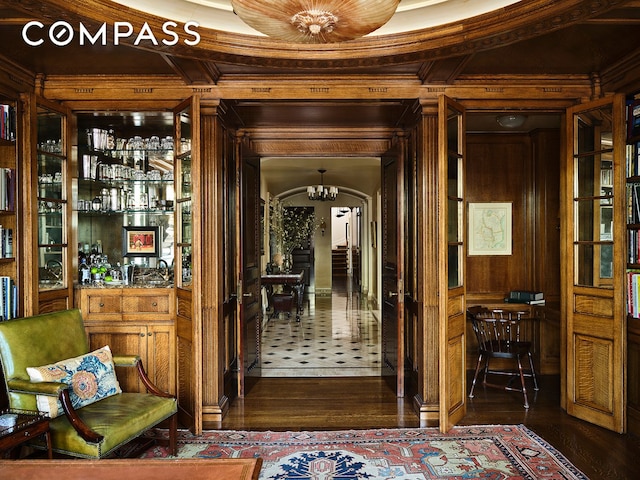interior space with wood walls, arched walkways, and ornamental molding