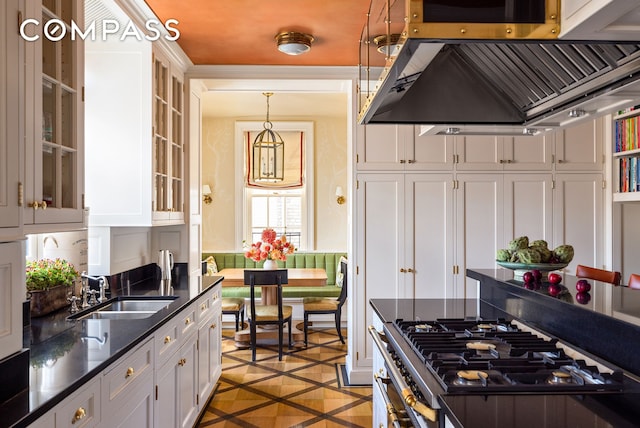 kitchen featuring range, pendant lighting, white cabinets, a sink, and extractor fan