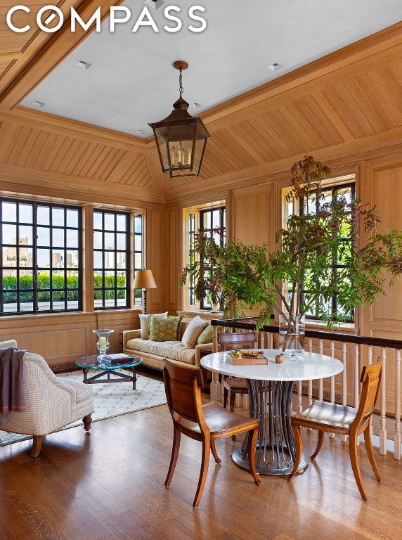 sitting room with wood walls, beamed ceiling, crown molding, coffered ceiling, and hardwood / wood-style flooring