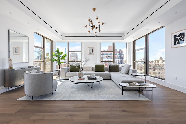 living room featuring a raised ceiling, an inviting chandelier, and wood finished floors