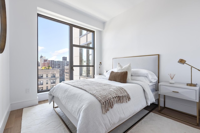 bedroom featuring baseboards, a city view, and wood finished floors