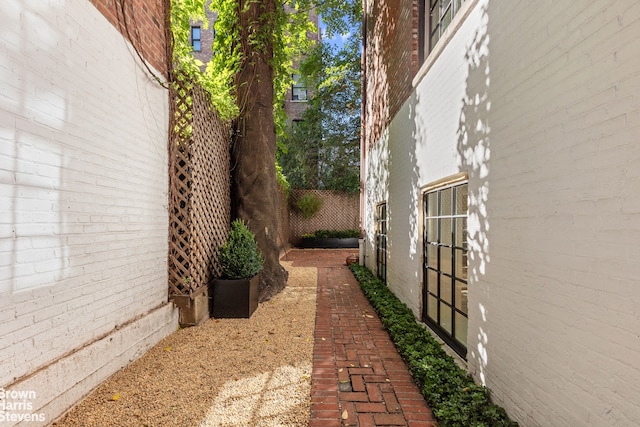 view of side of home with brick siding and fence