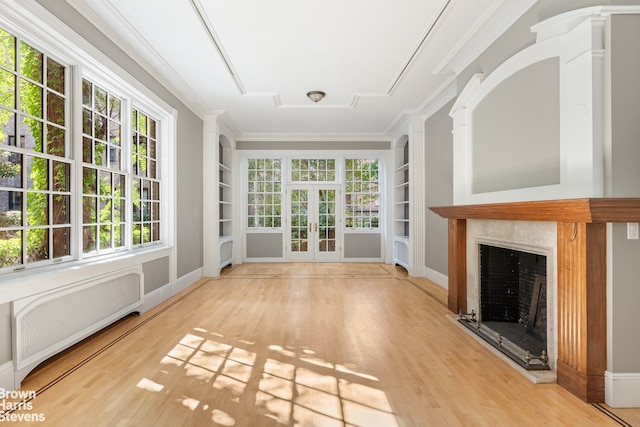 unfurnished sunroom featuring a wealth of natural light, a fireplace with raised hearth, and radiator