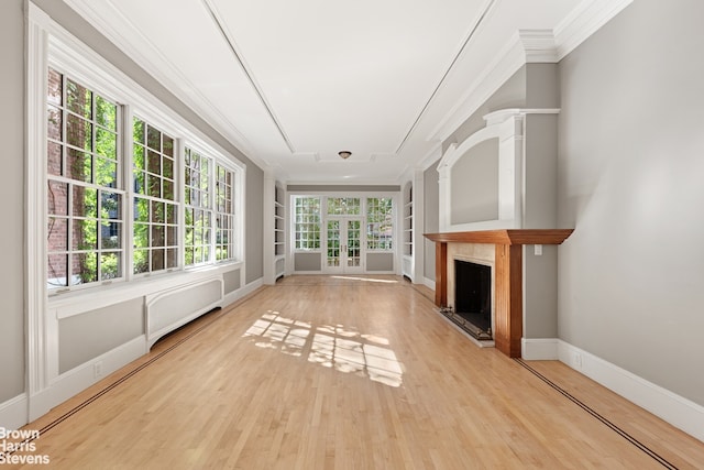 unfurnished living room featuring wood finished floors, crown molding, baseboards, and built in shelves